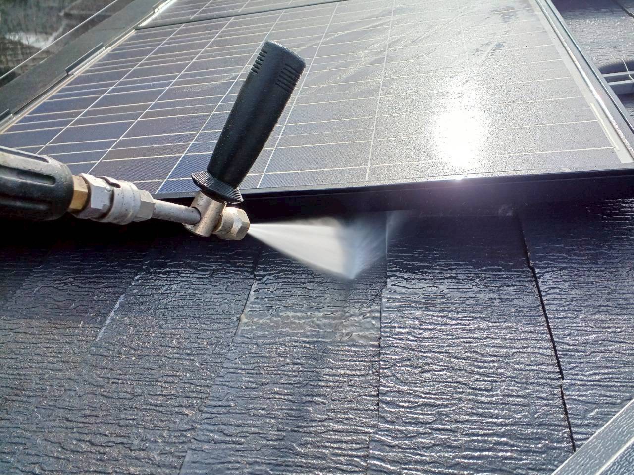 太陽光パネルの下のスレート屋根を高圧洗浄機で洗浄中